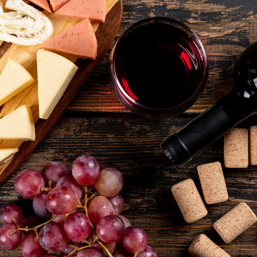 vista-superiore-di-vino-rosso-con-l-uva-e-il-formaggio-sul-tagliere-sull-orizzontale-di-legno-scuro_176474-4508